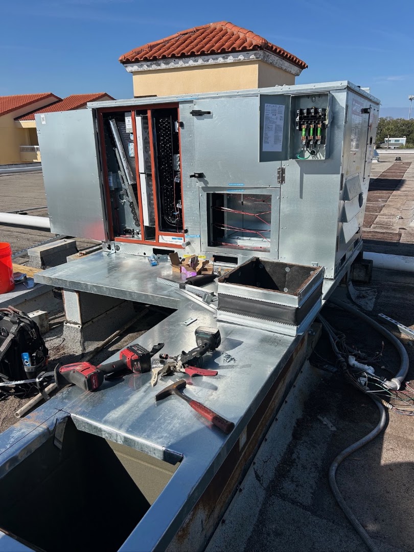 Rooftop package unit opened for service with tools laid out